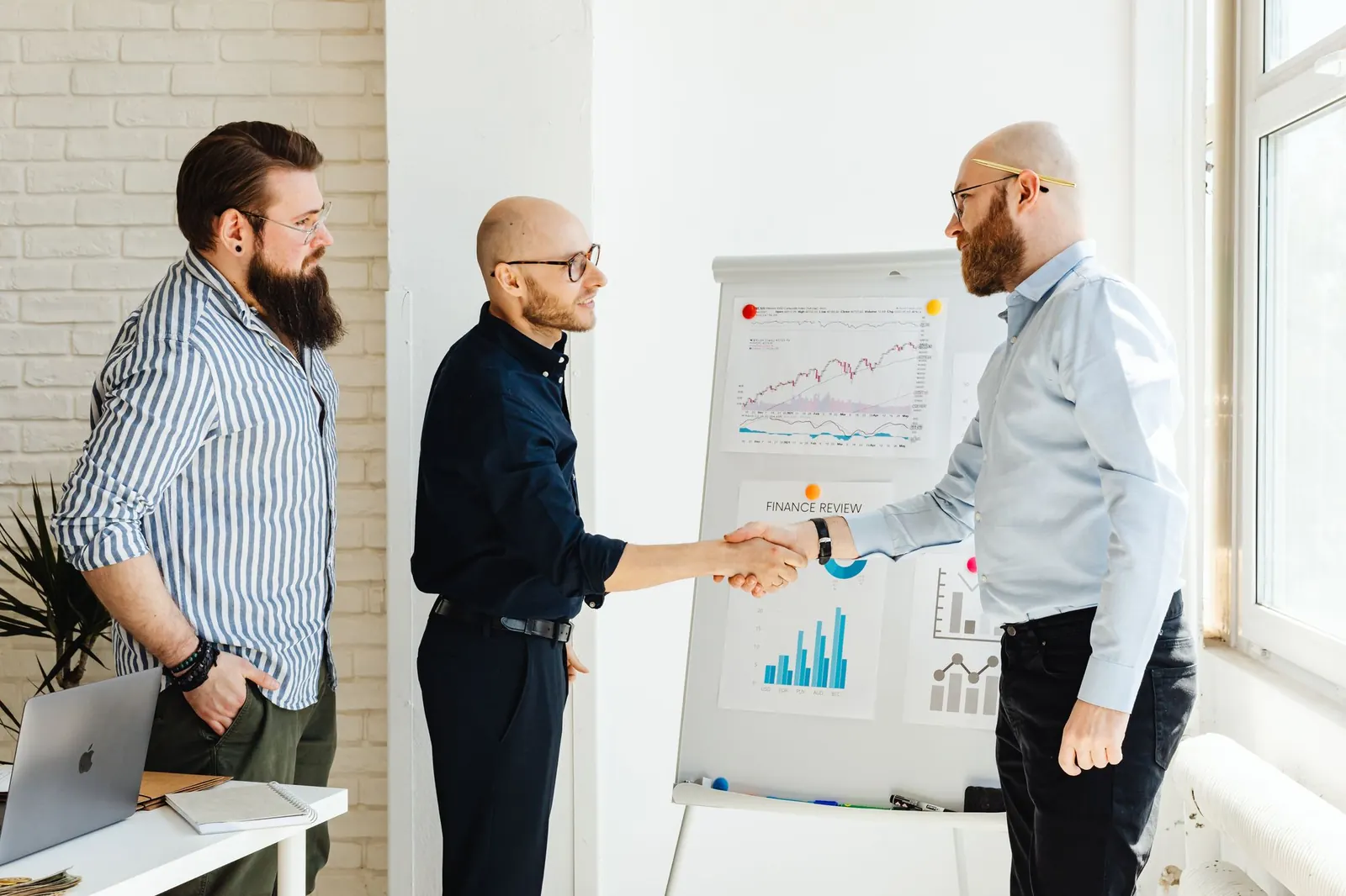 Colleagues shaking hands beside a flip chart of results
