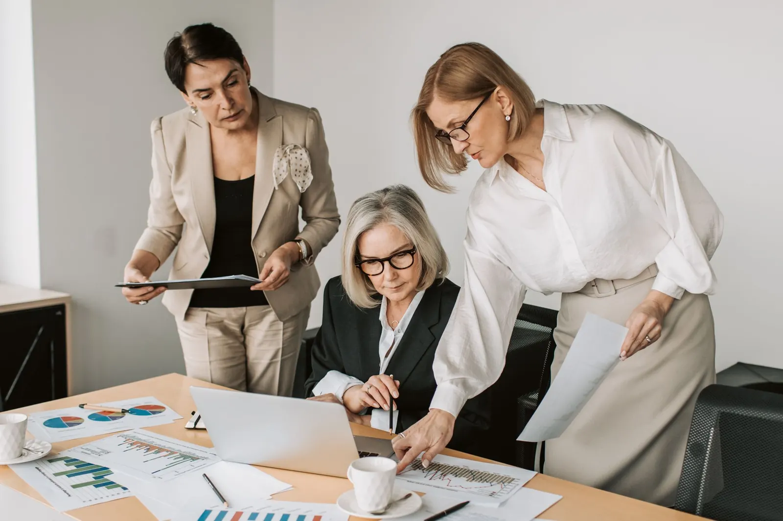 Three women reviewing documents and charts together at a desk